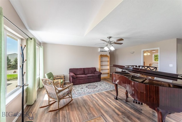 interior space featuring hardwood / wood-style floors, a wall unit AC, and ceiling fan