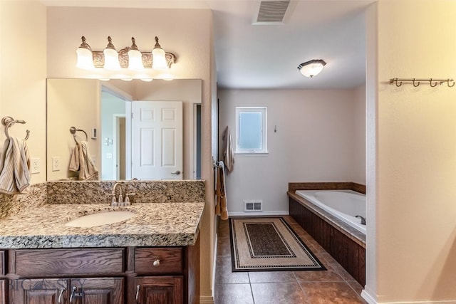 bathroom with tile patterned floors, tiled tub, and vanity