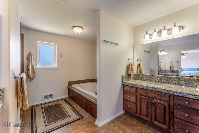 bathroom with tile patterned flooring, ceiling fan, a relaxing tiled tub, and vanity