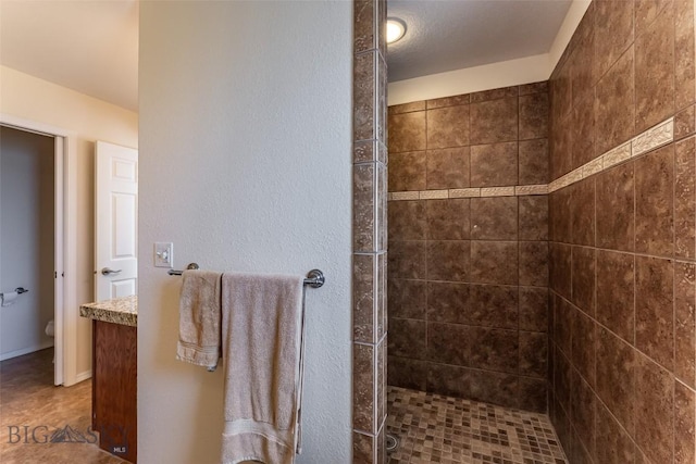 bathroom with tiled shower, vanity, and toilet