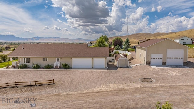 ranch-style home featuring a mountain view, a storage unit, and a garage