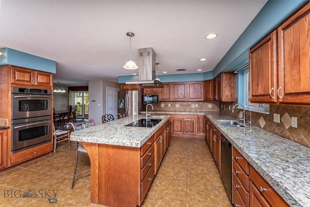 kitchen featuring tasteful backsplash, sink, black appliances, a breakfast bar area, and an island with sink