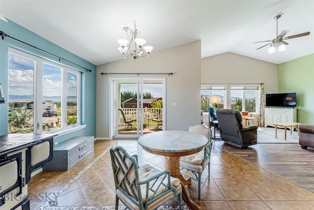 tiled dining space with ceiling fan with notable chandelier, lofted ceiling, and a wealth of natural light