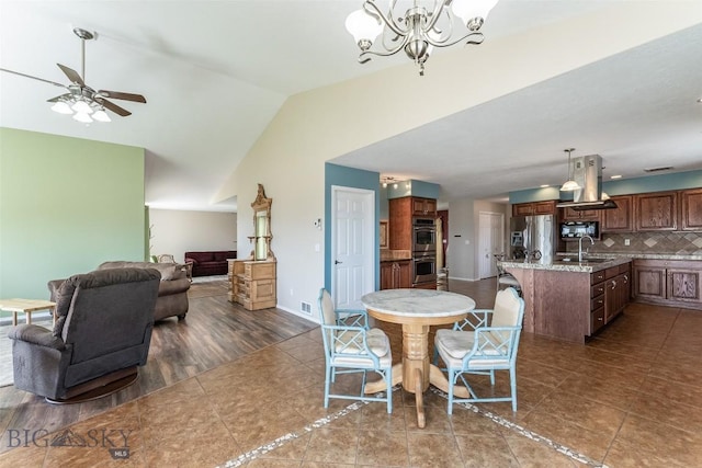 tiled dining room featuring vaulted ceiling, sink, and ceiling fan with notable chandelier