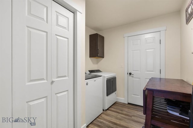 washroom with cabinets, hardwood / wood-style flooring, and washing machine and clothes dryer