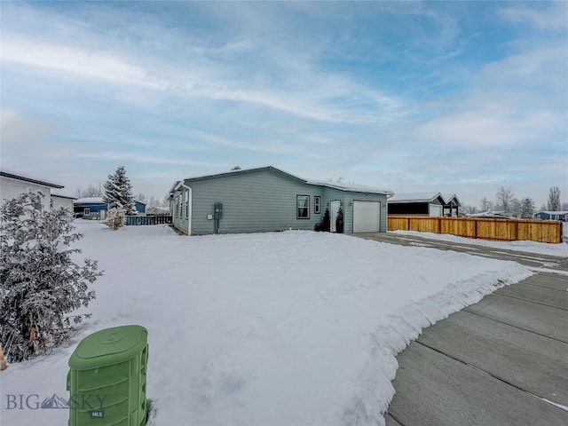 snow covered rear of property with a garage