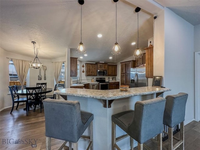 kitchen featuring appliances with stainless steel finishes, decorative light fixtures, kitchen peninsula, and sink