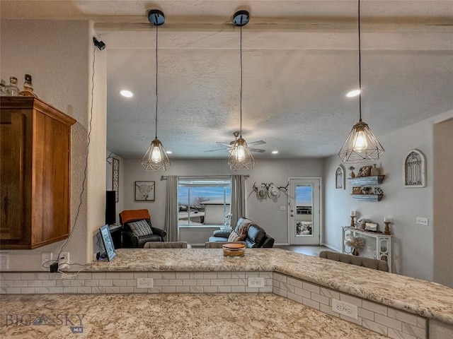 kitchen with ceiling fan, decorative light fixtures, light stone countertops, and a textured ceiling