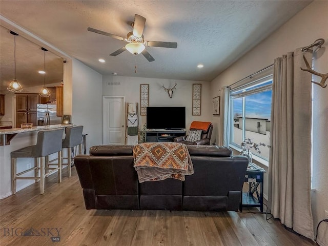 living room featuring ceiling fan, wood-type flooring, and a textured ceiling