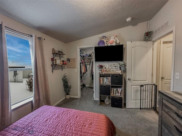 bedroom with a spacious closet, vaulted ceiling, a closet, and a textured ceiling