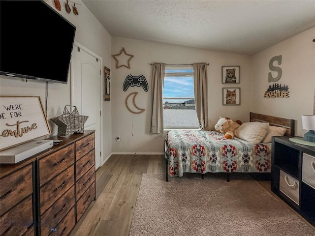 bedroom featuring lofted ceiling, a textured ceiling, and light hardwood / wood-style floors