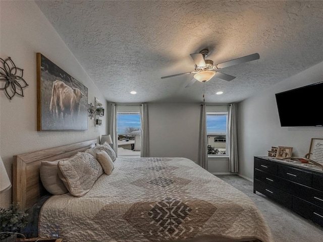 bedroom featuring ceiling fan, light carpet, and a textured ceiling