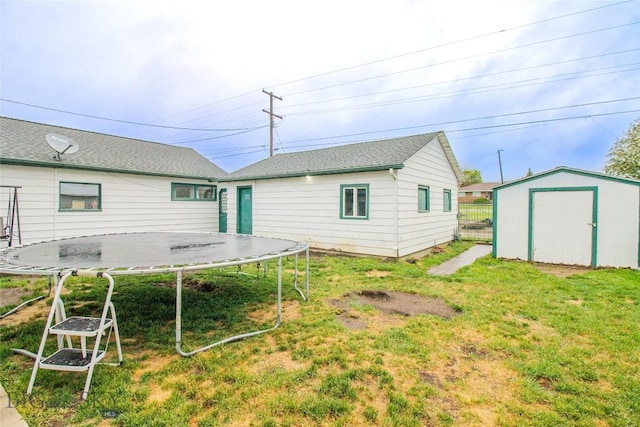 rear view of house with a lawn, a storage unit, and a trampoline