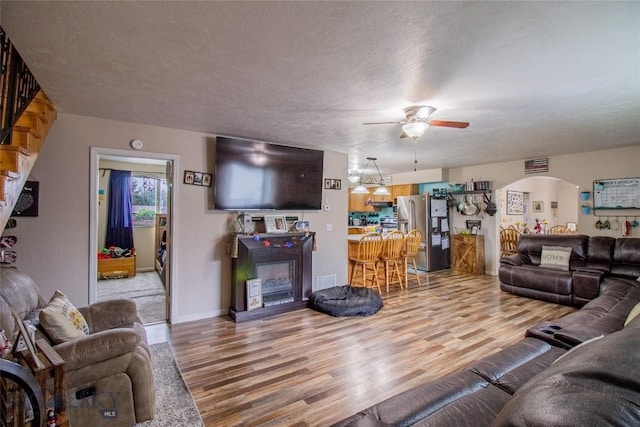 living room with hardwood / wood-style floors, a textured ceiling, and ceiling fan