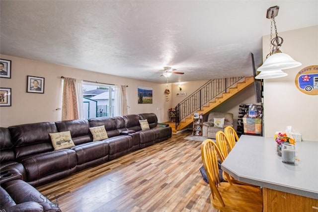 living room featuring ceiling fan, light hardwood / wood-style floors, and a textured ceiling