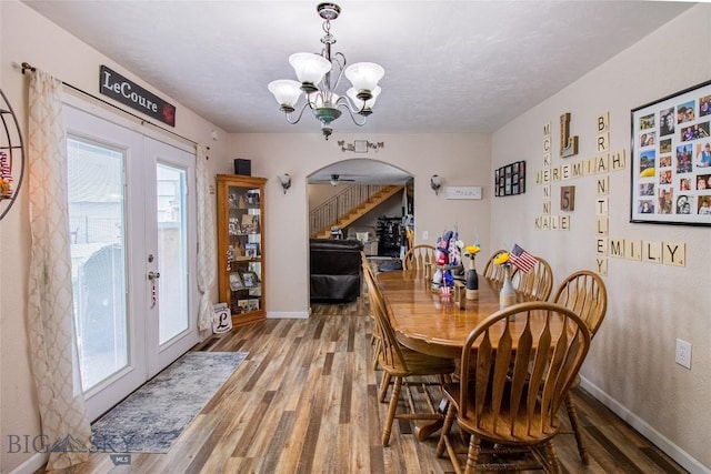 dining room with a wealth of natural light, french doors, wood-type flooring, and ceiling fan with notable chandelier