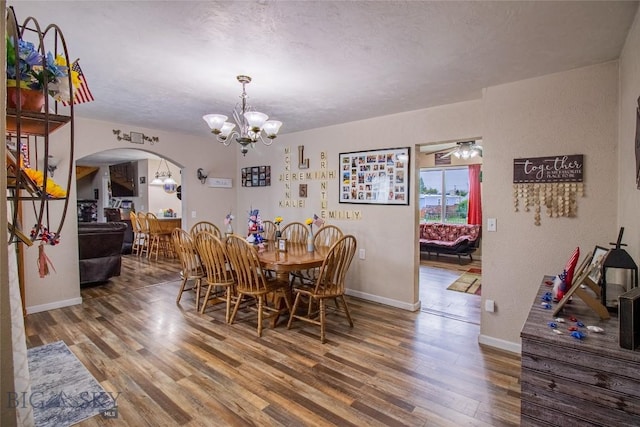 dining space featuring hardwood / wood-style floors, ceiling fan with notable chandelier, and a textured ceiling