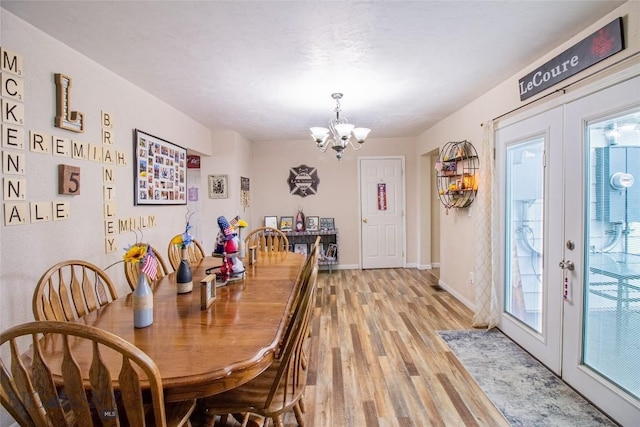 dining room with french doors, light hardwood / wood-style flooring, and an inviting chandelier