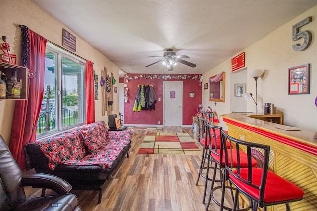 living room featuring hardwood / wood-style floors, ceiling fan, and bar area