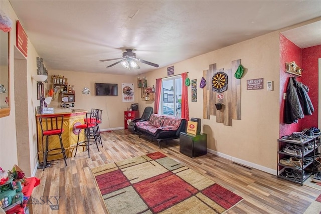 living room with bar, ceiling fan, and hardwood / wood-style flooring