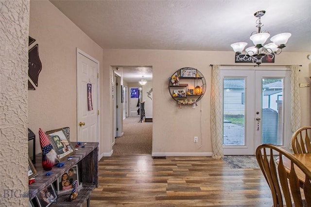 entrance foyer with french doors, dark hardwood / wood-style flooring, a textured ceiling, and an inviting chandelier