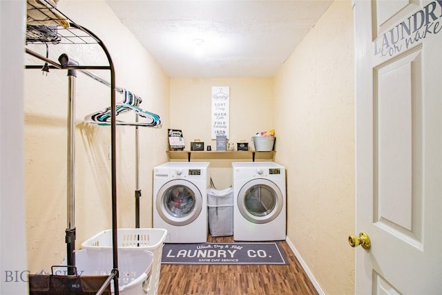 laundry room with washing machine and dryer, wood-type flooring, and a textured ceiling