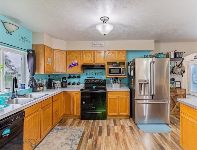 kitchen featuring light wood-type flooring, a textured ceiling, sink, and black appliances