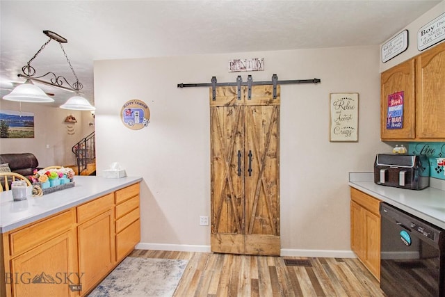 kitchen with black dishwasher, pendant lighting, a barn door, and light wood-type flooring