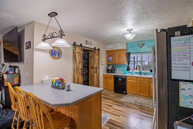 kitchen featuring kitchen peninsula, a barn door, dishwasher, and decorative light fixtures