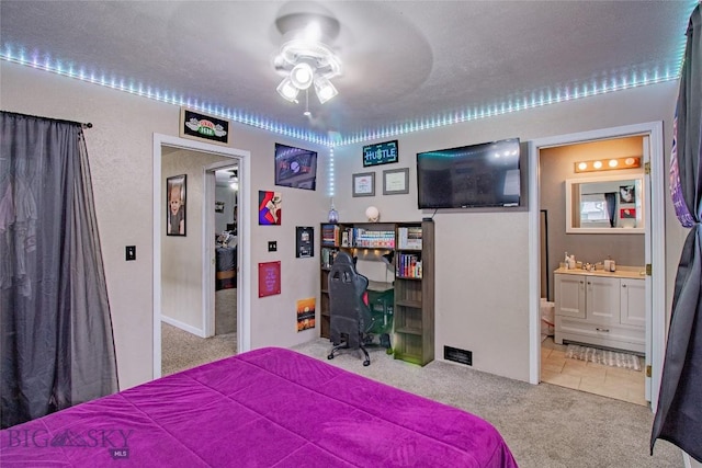 bedroom with ensuite bath, ceiling fan, carpet floors, and a textured ceiling