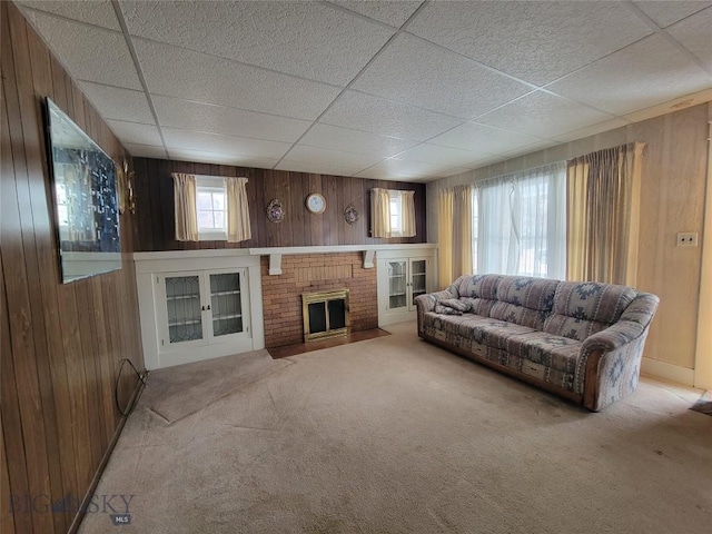 carpeted living room featuring wooden walls and a fireplace