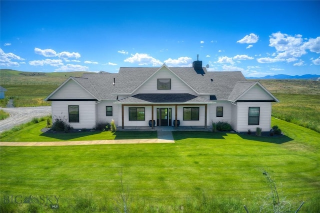 back of property featuring a mountain view and a lawn