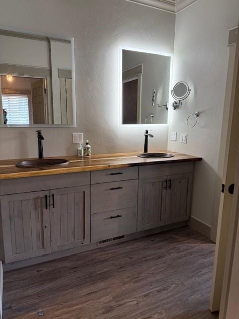 bathroom with wood-type flooring, vanity, and ornamental molding