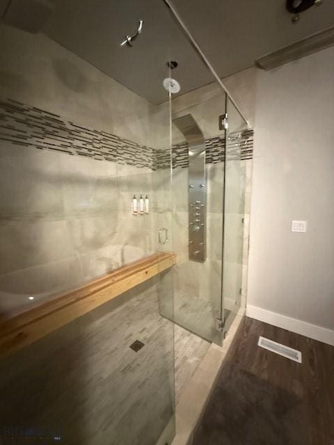 bathroom with tiled shower and wood-type flooring