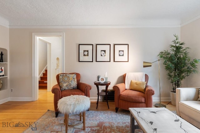 sitting room with a textured ceiling, light wood-type flooring, and ornamental molding