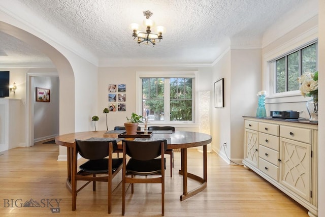 dining space featuring a textured ceiling, a notable chandelier, light wood-type flooring, and crown molding