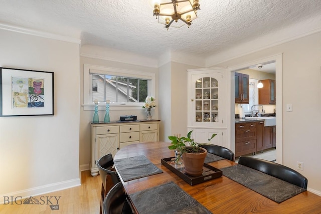 dining area with a notable chandelier, a textured ceiling, and light wood-type flooring