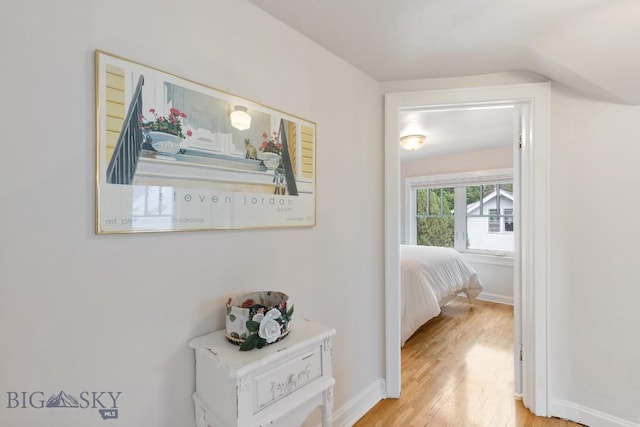 hallway featuring light wood-type flooring and vaulted ceiling