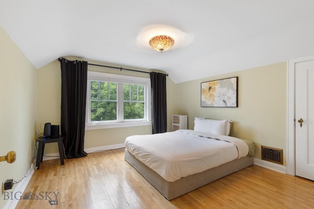 bedroom featuring lofted ceiling and light wood-type flooring