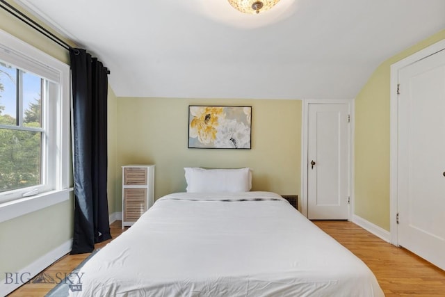 bedroom featuring wood-type flooring, multiple windows, and lofted ceiling