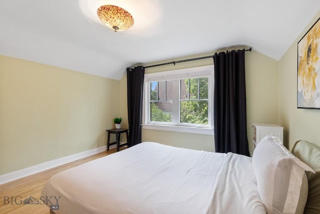 bedroom with hardwood / wood-style floors and lofted ceiling