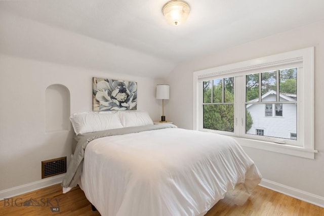 bedroom with hardwood / wood-style floors and vaulted ceiling