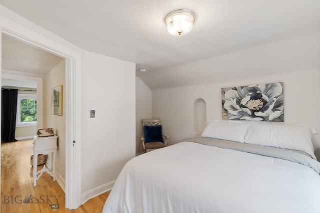 bedroom featuring light wood-type flooring and vaulted ceiling