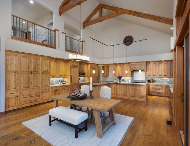 dining space with lofted ceiling with beams, light wood-style flooring, and visible vents