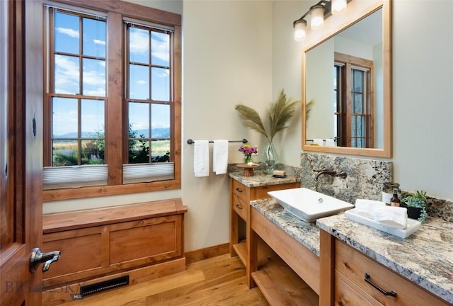 full bathroom with a healthy amount of sunlight, visible vents, a sink, and wood finished floors