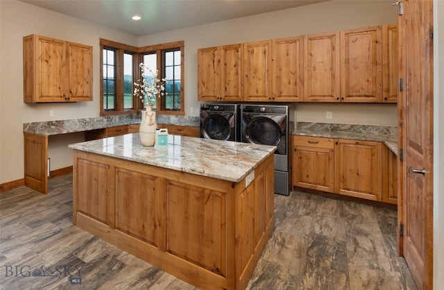 kitchen featuring baseboards, dark wood finished floors, a kitchen island, light stone counters, and separate washer and dryer