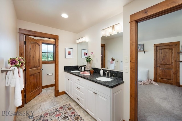 full bath with a sink, baseboards, and double vanity