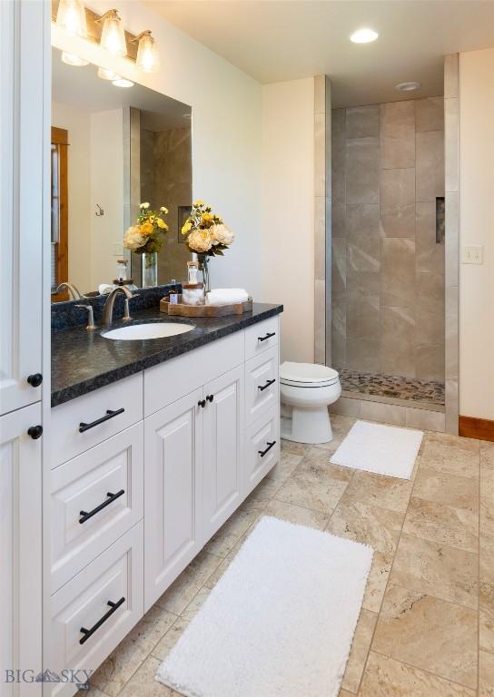 full bathroom with recessed lighting, toilet, vanity, tiled shower, and baseboards