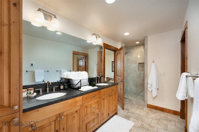 bathroom featuring a stall shower, a sink, baseboards, and double vanity