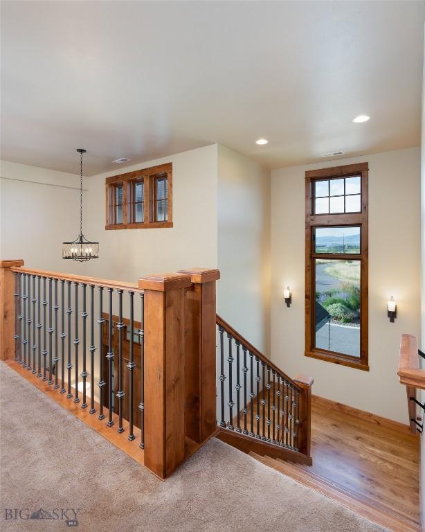 stairs with wood finished floors, a notable chandelier, and recessed lighting